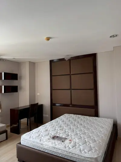 Spacious bedroom with modern decor and natural light, featuring a comfortable bed and stylish furnishings.