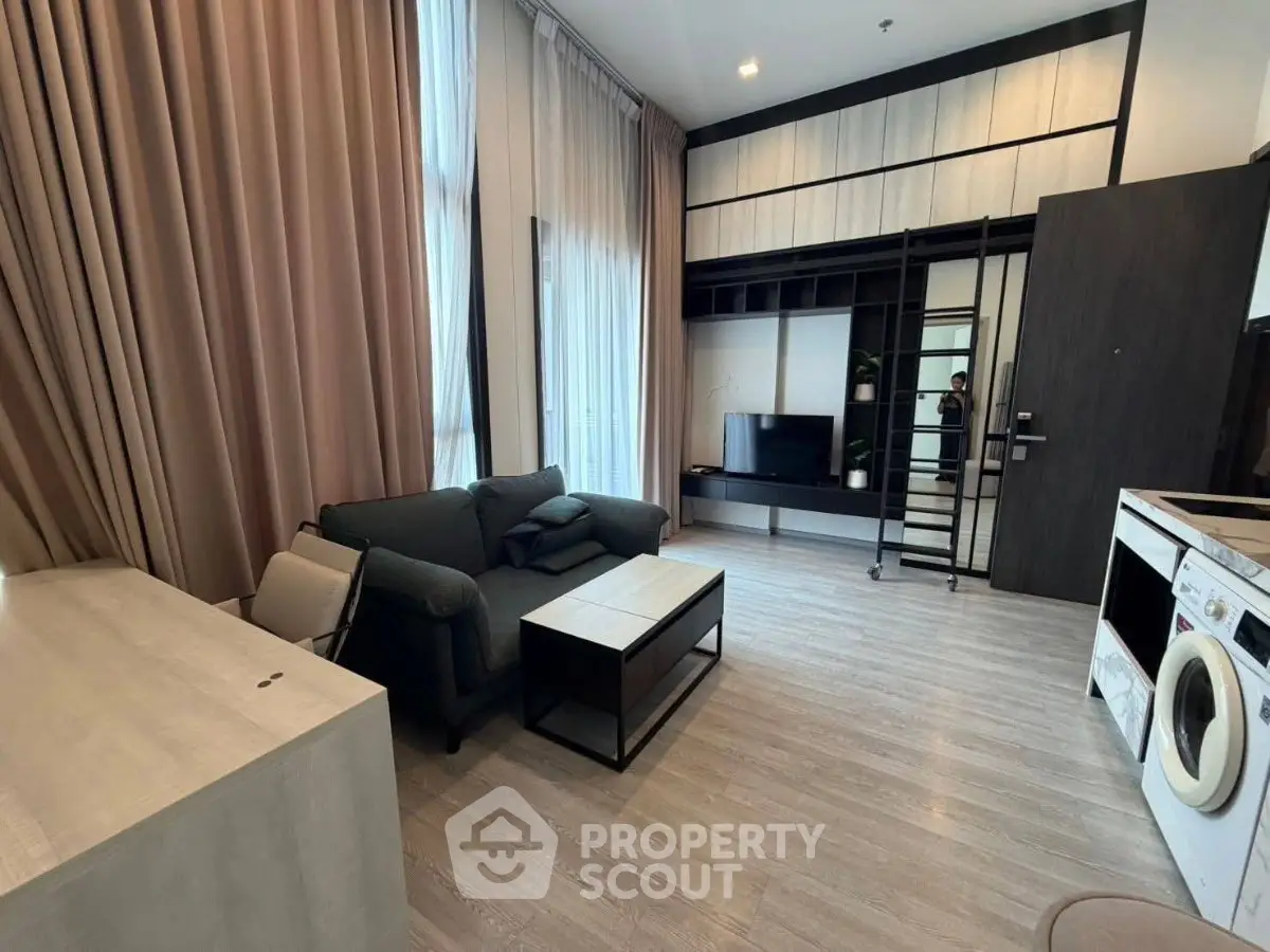Modern living room with high ceilings, stylish furniture, and integrated appliances in a contemporary apartment.