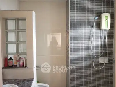 Modern bathroom with sleek shower and tiled walls, featuring a stylish vanity area.