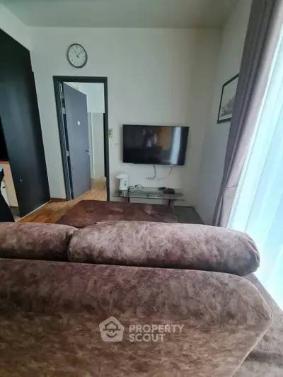 Cozy living room with plush brown sofa and wall-mounted TV, perfect for relaxation.