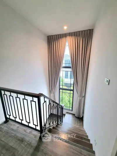 Elegant staircase with large window and modern railing in a stylish home