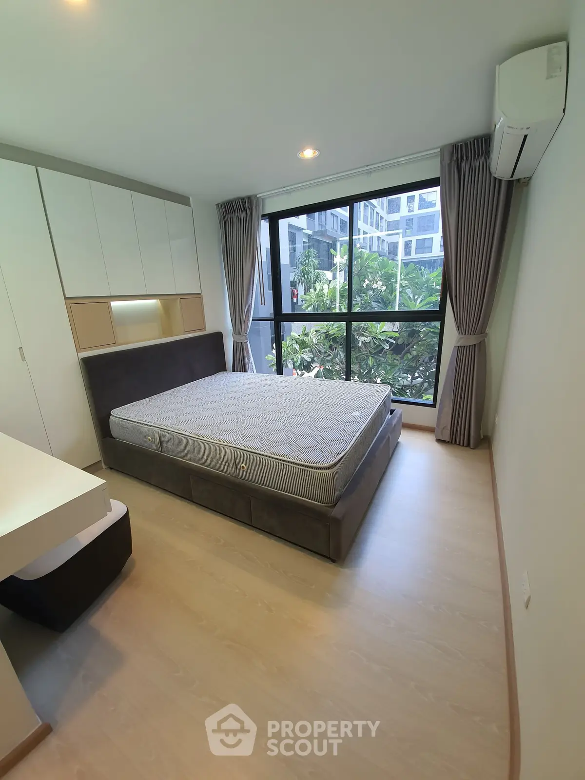 Modern bedroom with large window and built-in storage in a stylish apartment.