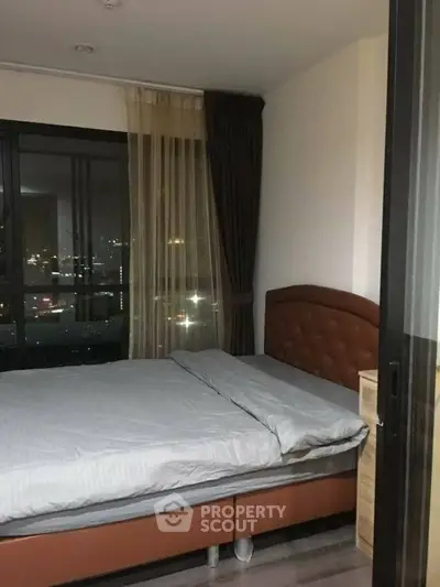 Cozy bedroom with city view, featuring a comfortable bed and elegant curtains.