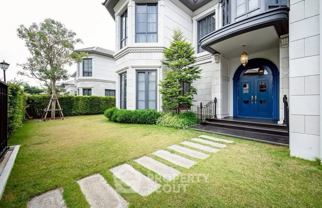 Elegant exterior of luxury home with manicured lawn and grand entrance.