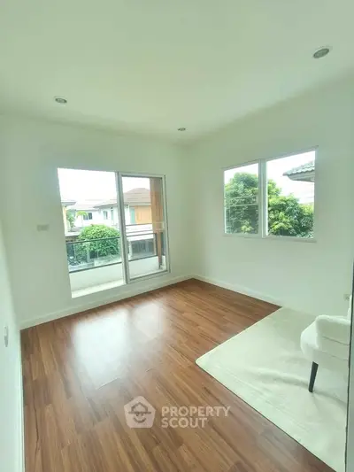 Bright and airy room with wooden flooring and large windows offering a serene view, perfect for a cozy living space.