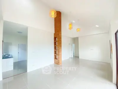 Spacious modern living room with unique wooden column and elegant lighting fixtures.