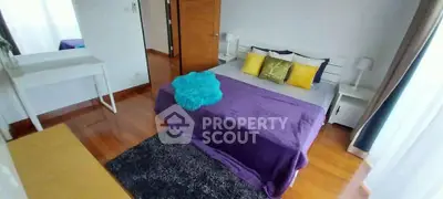 Spacious bedroom with vibrant decor and natural light, featuring a cozy bed and stylish furnishings.