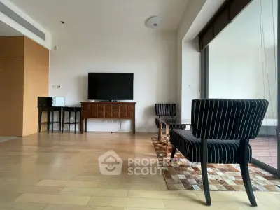Spacious living room with modern furniture and large TV, featuring wooden flooring and natural light.