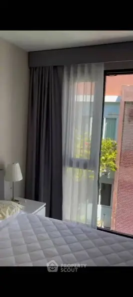 Modern bedroom with large window and stylish curtains, offering a bright and airy atmosphere.