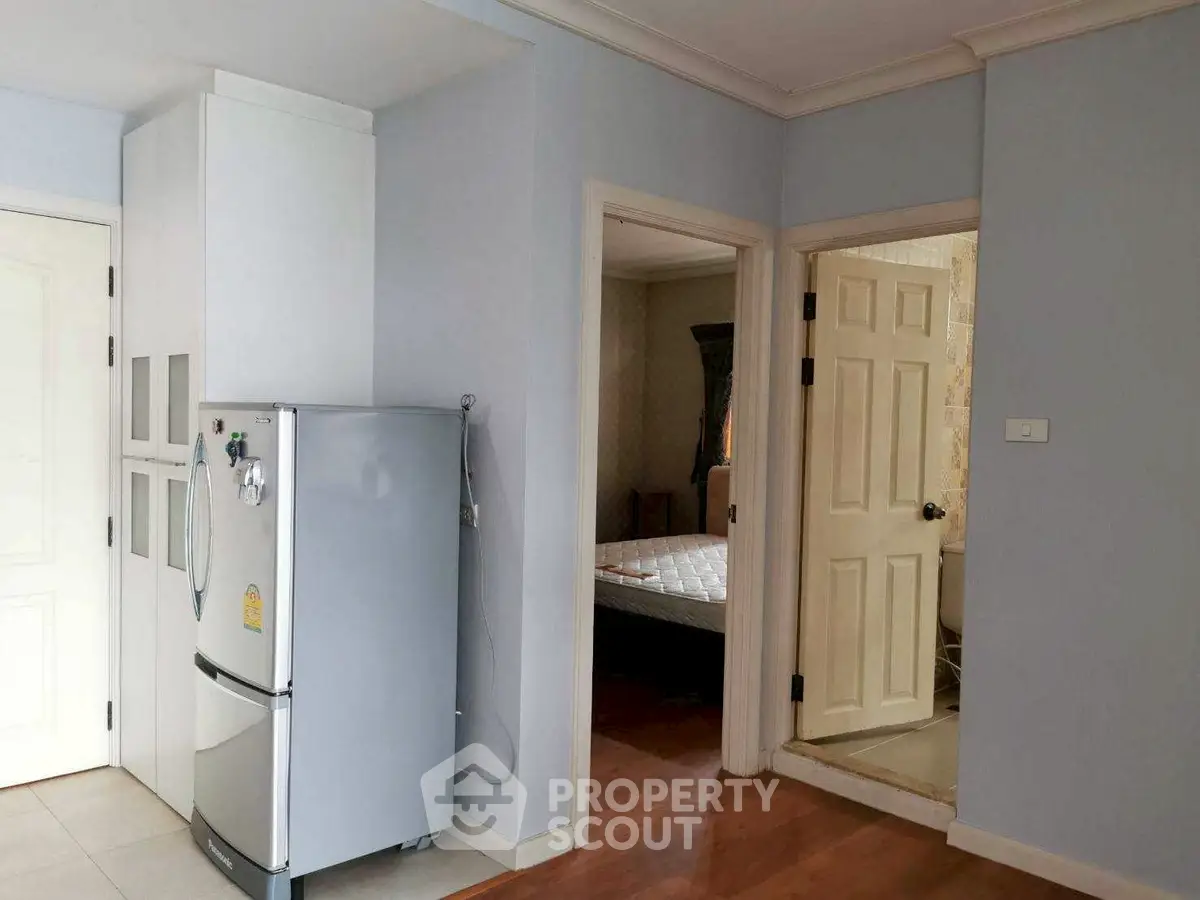Cozy apartment interior with fridge, bedroom, and bathroom access.