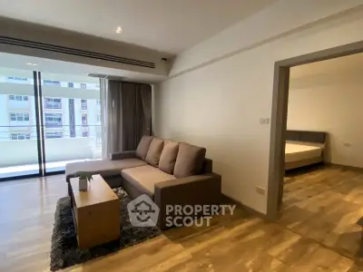 Spacious modern living room with large windows and cozy seating in a stylish apartment.