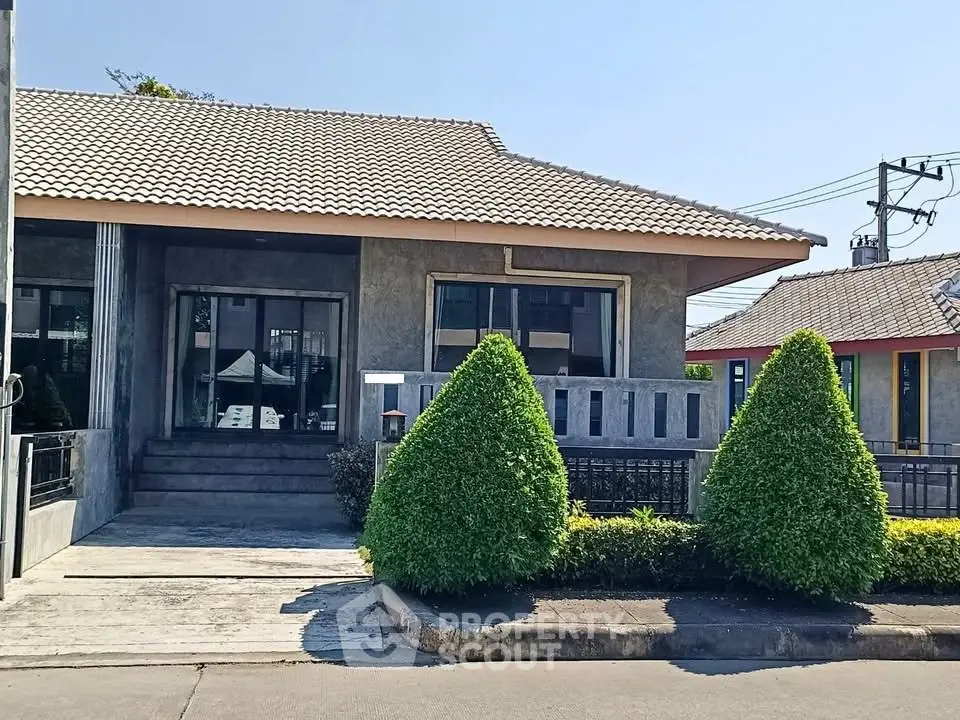 Charming single-story house with modern design and manicured shrubs, perfect for family living.