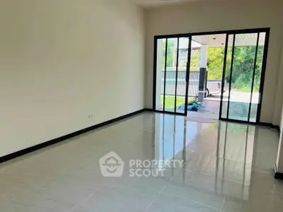 Spacious living room with large glass doors leading to a lush garden view.
