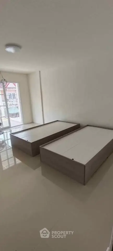 Spacious bedroom with two modern platform beds and large window for natural light.