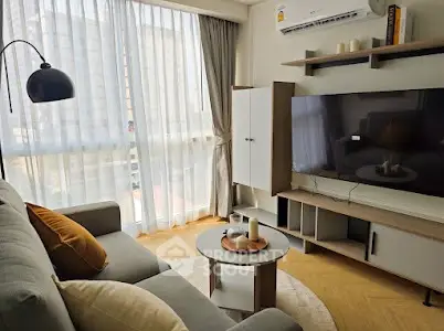 Modern living room with large window, cozy sofa, and stylish TV setup.