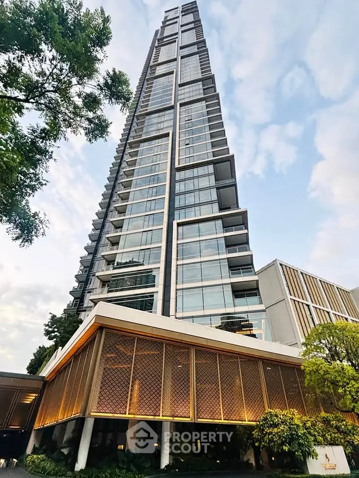 Stunning modern high-rise building with sleek glass facade and lush greenery at the base.
