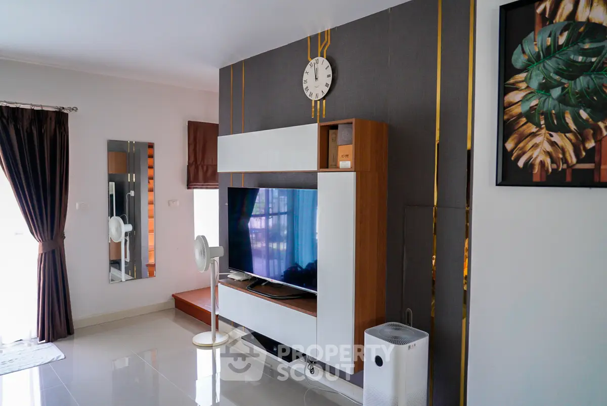 Modern living room with stylish decor, featuring a sleek entertainment center and large wall-mounted TV.