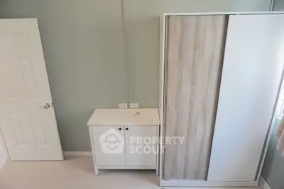 Minimalist bedroom with ample natural light, featuring a large sliding closet and a compact white storage cabinet, ideal for modern living.