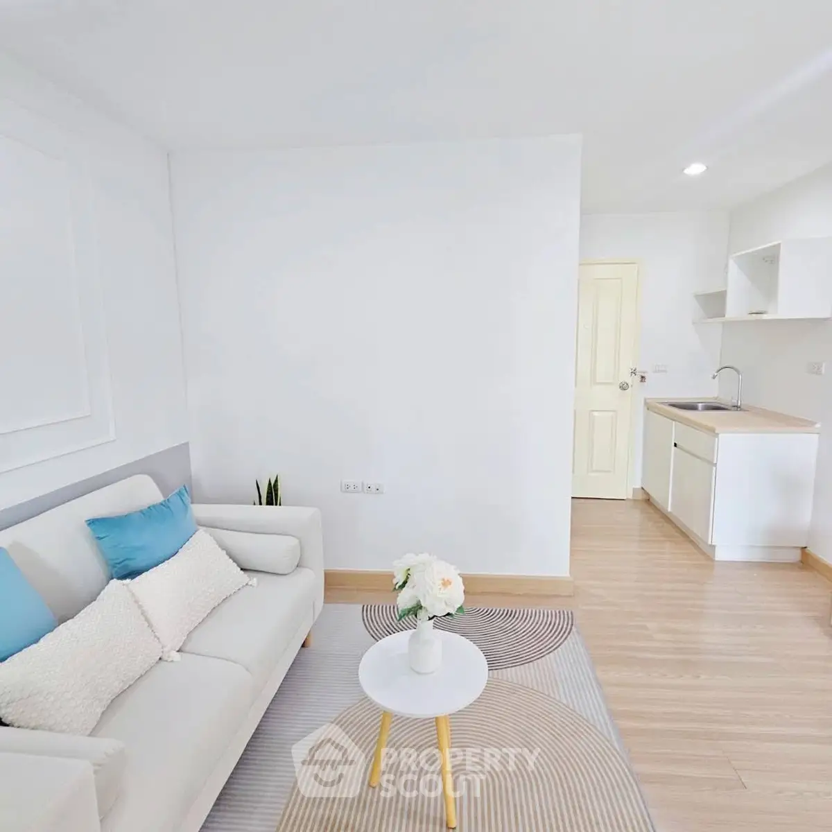 Bright and modern living room with cozy sofa and compact kitchen area, perfect for urban living.
