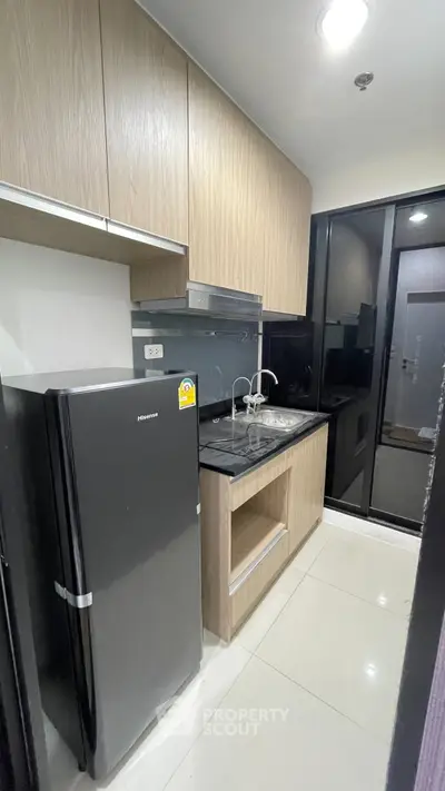 Modern compact kitchen with sleek cabinetry and stainless steel appliances in a stylish apartment.