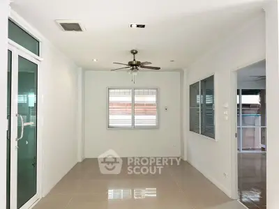 Spacious interior room with ceiling fan and large windows, perfect for versatile living space.