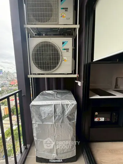 Modern apartment balcony with air conditioning units and city view.