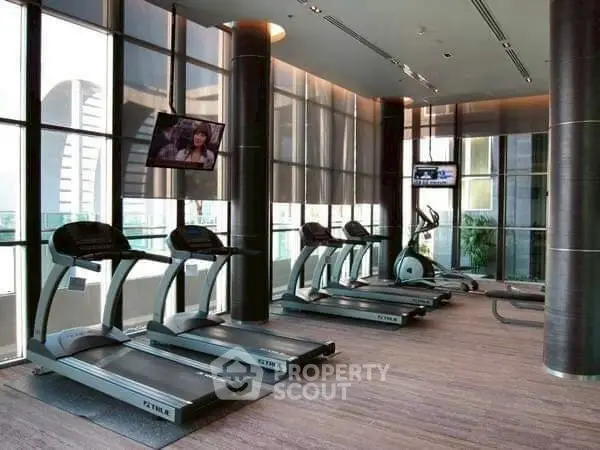 Modern gym with treadmills and large windows in luxury building.