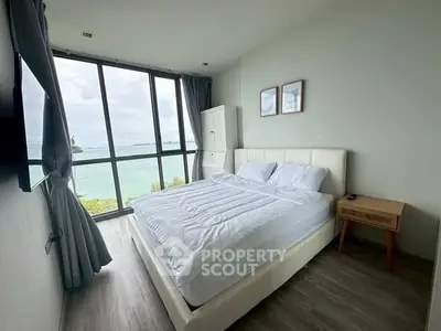 Stunning bedroom with floor-to-ceiling windows offering breathtaking ocean views, modern decor, and cozy ambiance.
