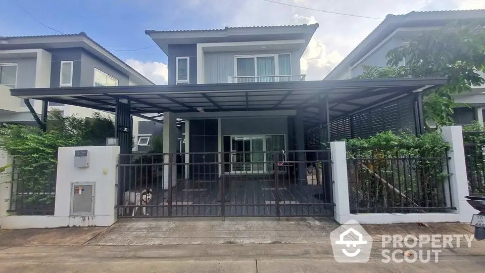 Modern two-story house with gated entrance and covered parking in suburban neighborhood.