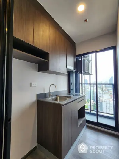 Modern compact kitchen with city view and sleek wooden cabinetry