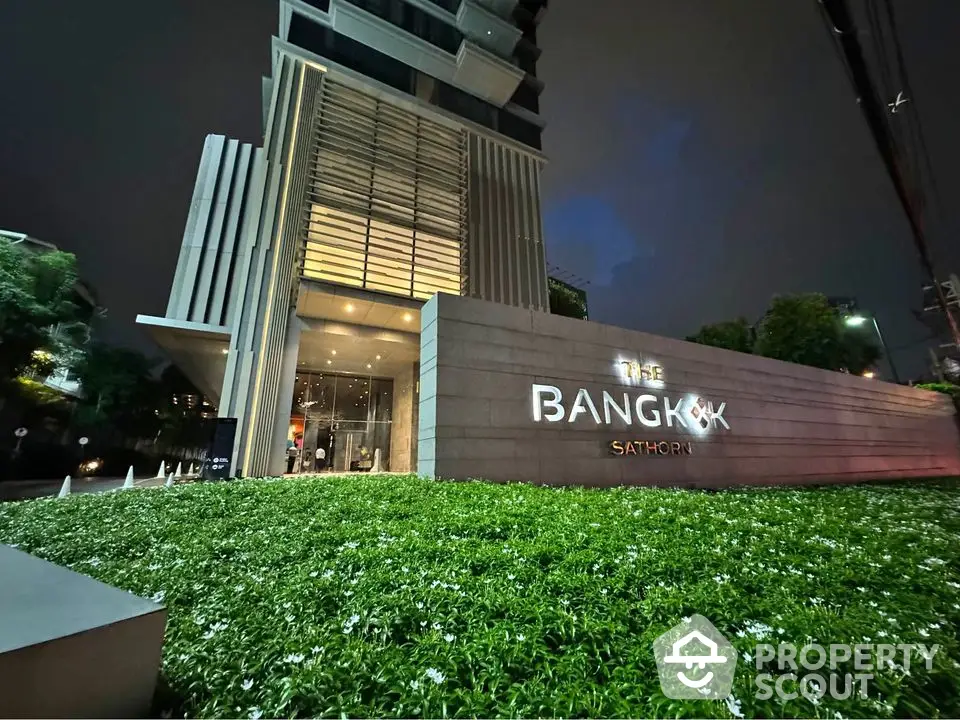 Luxurious Bangkok Sathorn building entrance with modern architecture and lush greenery