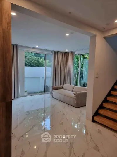 Spacious living room with modern design and large windows overlooking greenery.