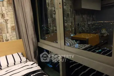 Cozy bedroom with city view through large window, modern decor and striped bedding.