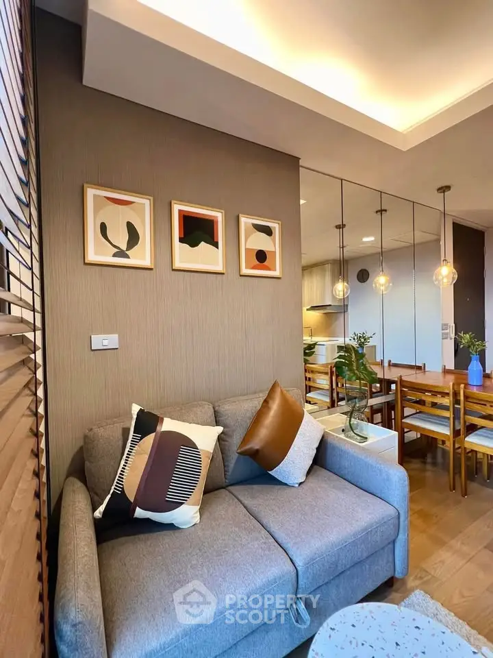 Stylish living room with modern decor and open kitchen layout, featuring elegant lighting and cozy seating.