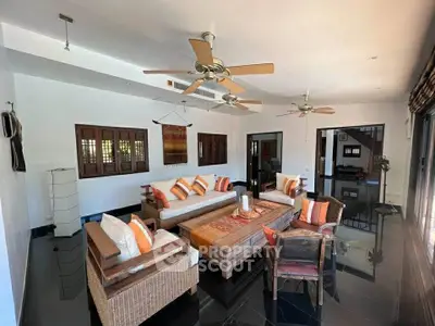 Spacious living room with stylish wicker furniture and ceiling fans