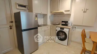 Modern kitchen with stainless steel fridge, washing machine, and microwave in cozy apartment.