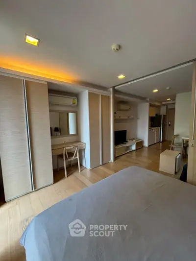 Modern bedroom with wooden flooring and built-in wardrobe, featuring a cozy workspace and sleek design.