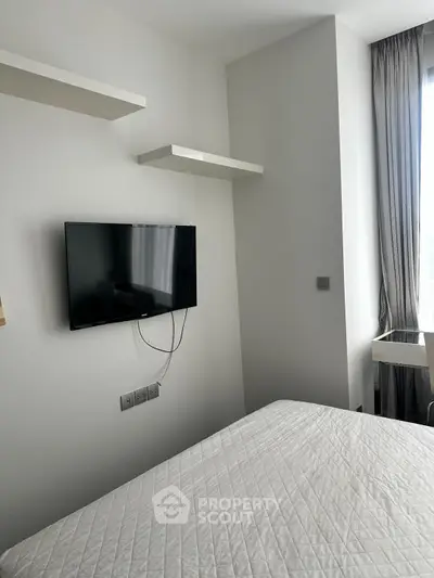 Modern bedroom with wall-mounted TV and minimalist decor