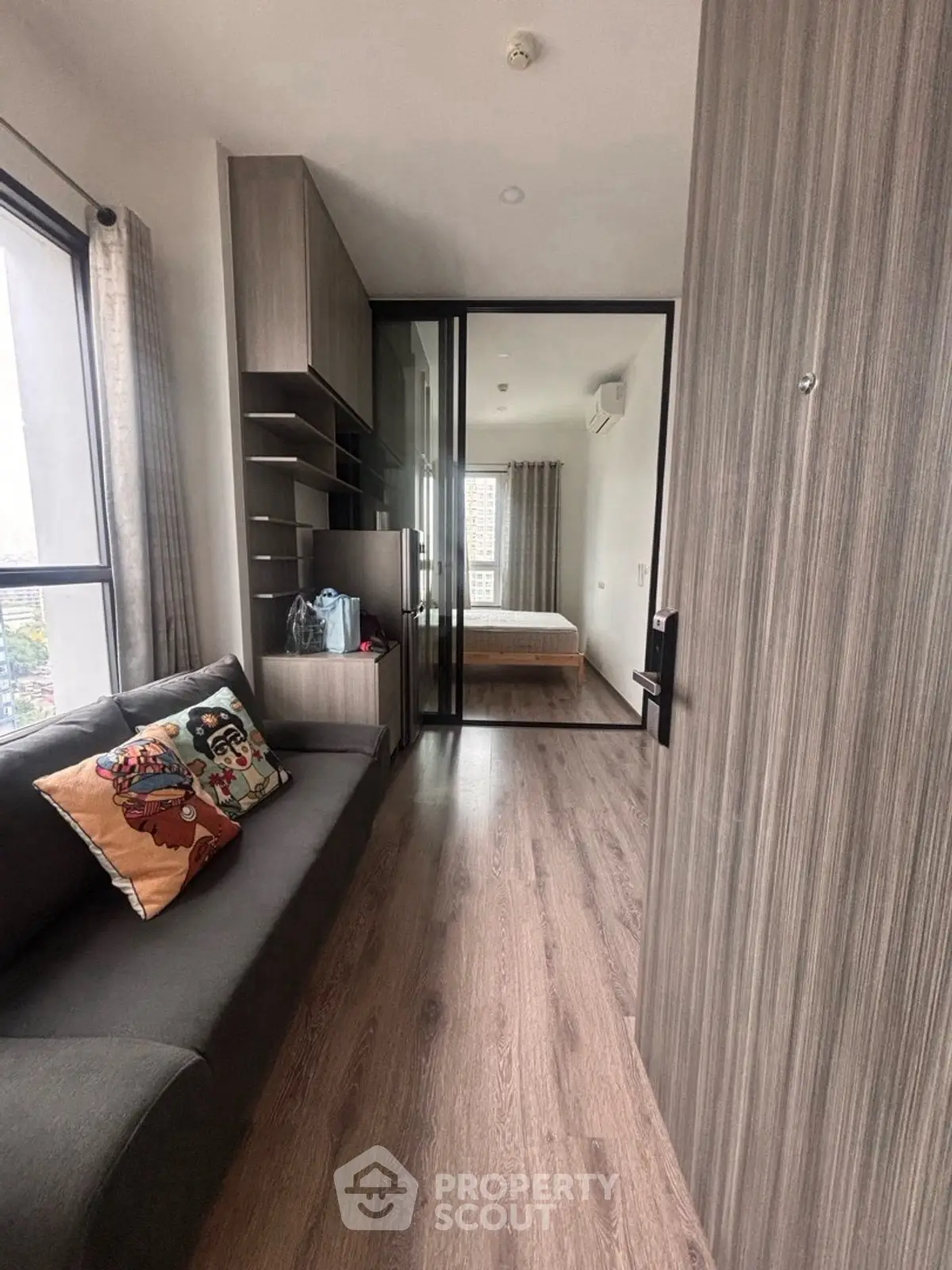 Modern apartment interior with cozy living area and bedroom separated by glass partition.