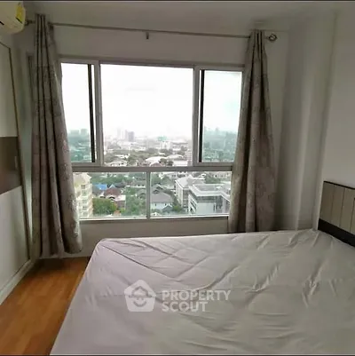 Spacious bedroom with large window offering stunning city views