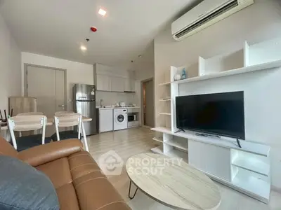 Modern living room with open kitchen, featuring sleek furniture and appliances, ideal for urban living.
