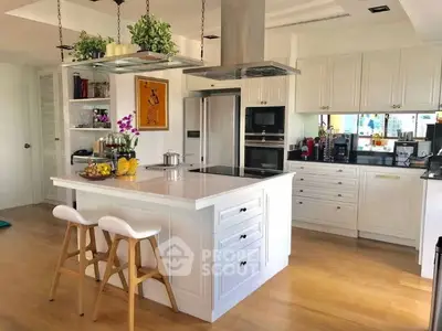 Modern kitchen with island, white cabinets, and wooden flooring