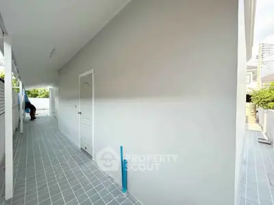 Spacious exterior corridor with tiled flooring and white walls in modern property