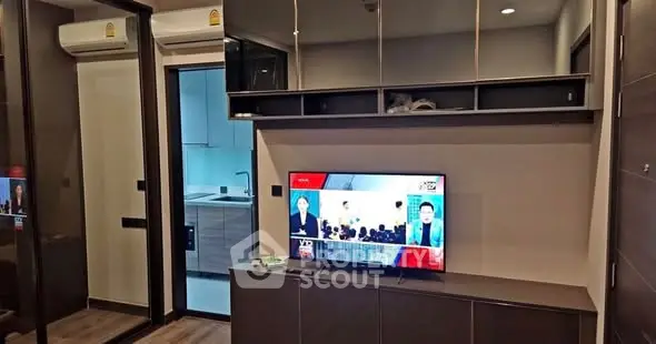 Modern living room with TV and view into sleek kitchen