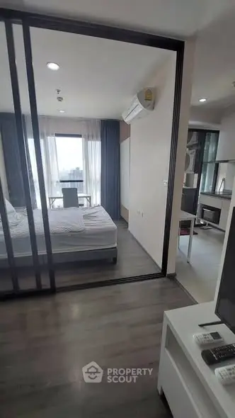 Modern bedroom with sliding glass doors and natural light in a stylish apartment.