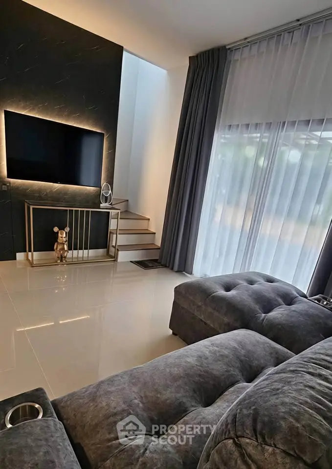 Luxurious modern living room with plush seating and large TV, featuring elegant decor and natural light.