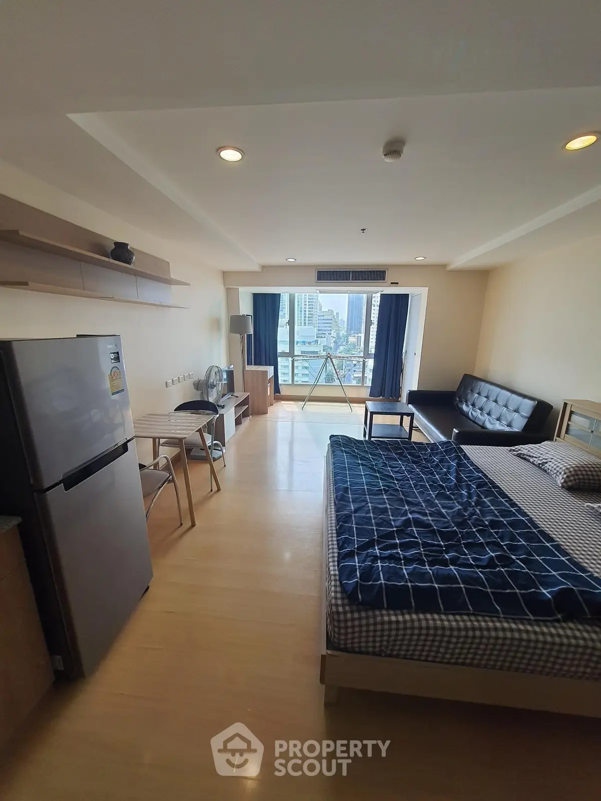 Modern studio apartment with open layout and city view, featuring a cozy living area and kitchenette.