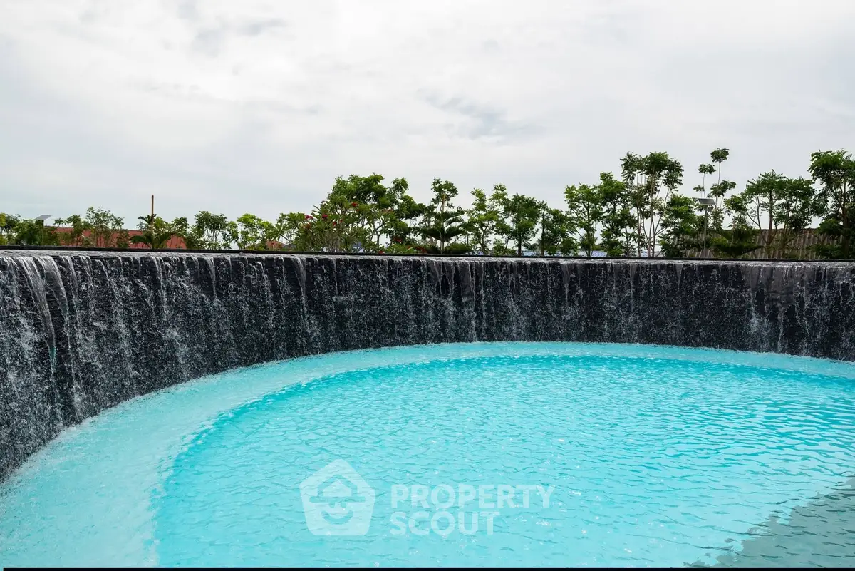 Luxurious pool with cascading waterfall in a serene garden setting.