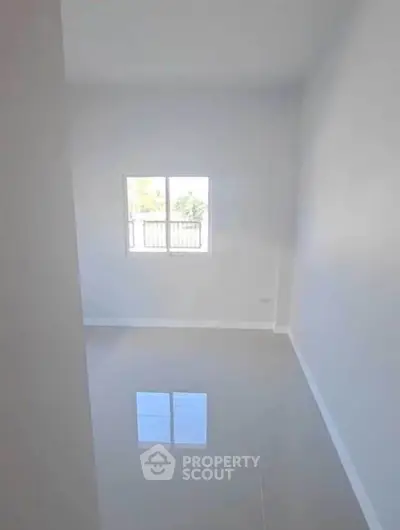 Minimalist empty room with glossy floor and bright window view.