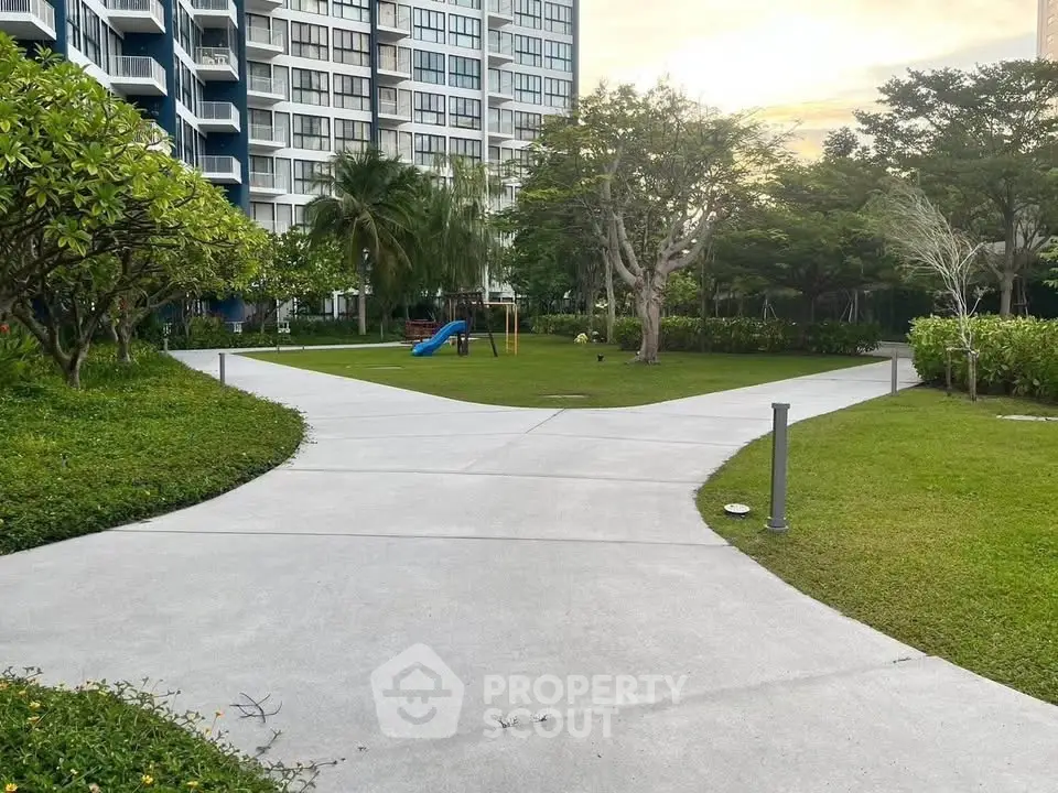 Beautiful garden pathway in modern residential complex with lush greenery and playground.